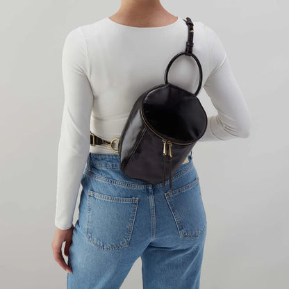person wearing jeans and a white top with black Sheila Sling Bag over their shoulder