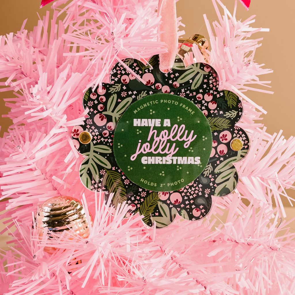 flat scallop edge ornament with pink and green holly imagery on a pink tree