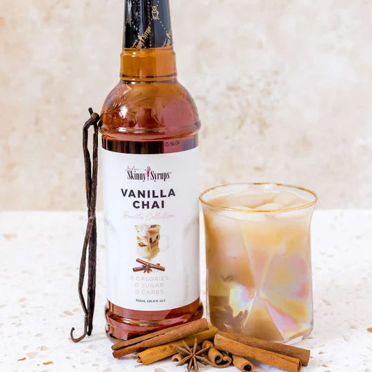 bottle of Vanilla Chai skinny syrup set next to an ice chai latte and cinnamon sticks.