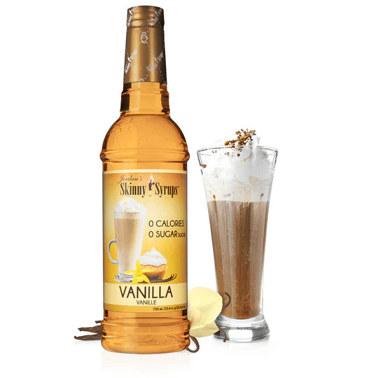 bottle of Vanilla skinny syrup set next to a tall glass of iced coffe with whipped topping.