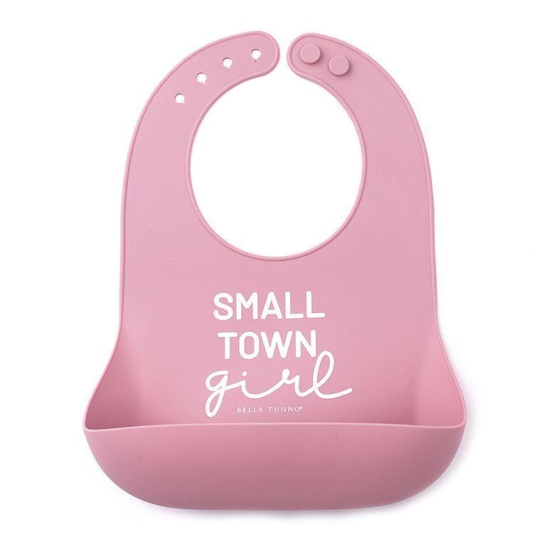 pink silicone wonder bib with wording small town girl and displayed against a white background