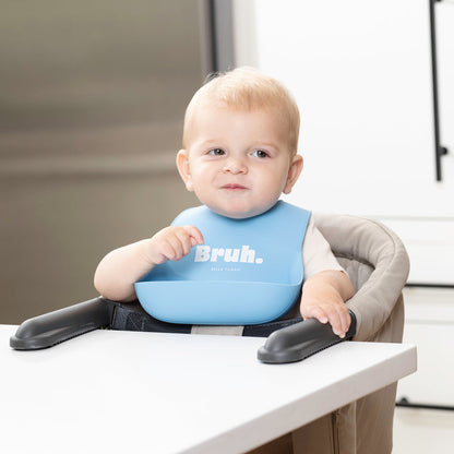 baby siting in highchair wearing "bruh" silicone bib.