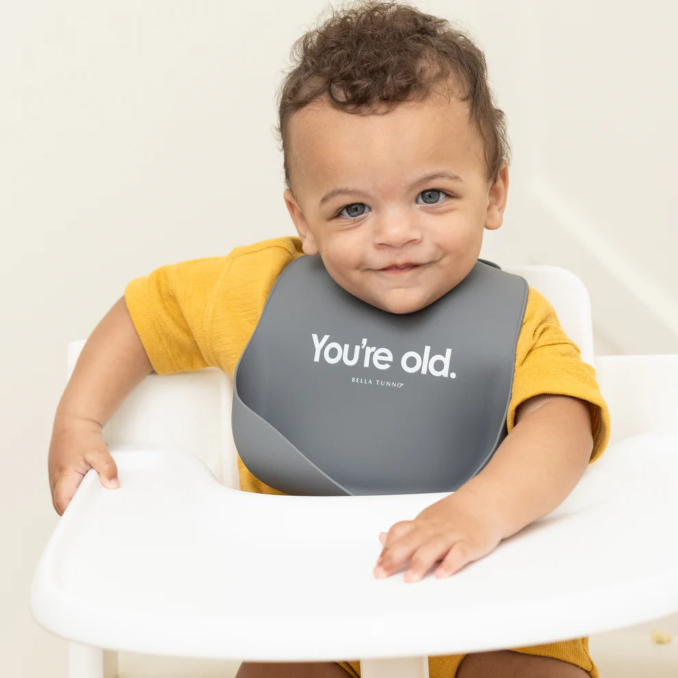 baby sitting in highchair wearing you're old bib