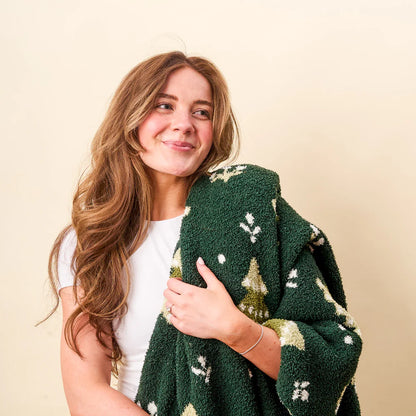 person with Christmas Trees blanket draped over their shoulder.