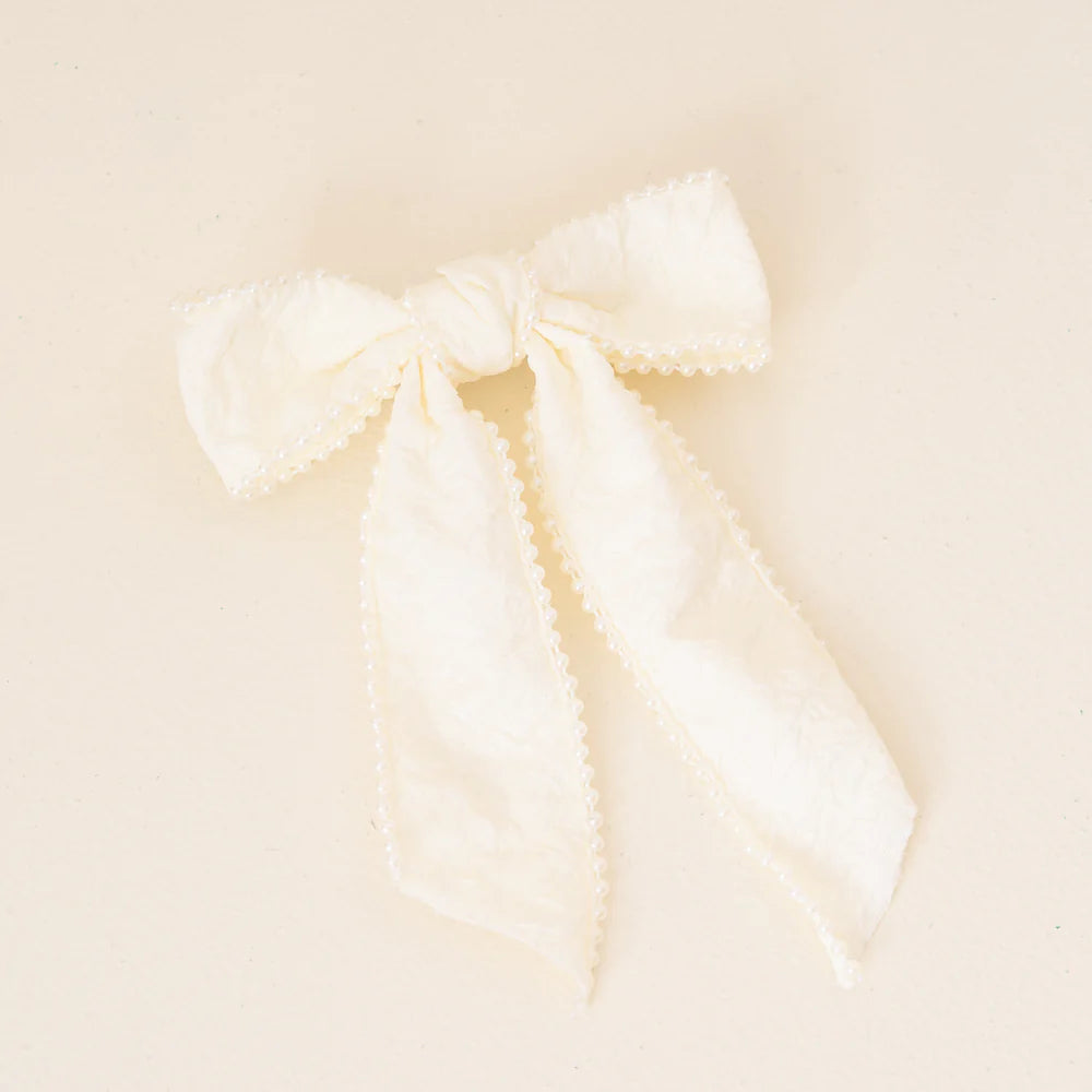 cream bow with pearls shown on an off-white background.