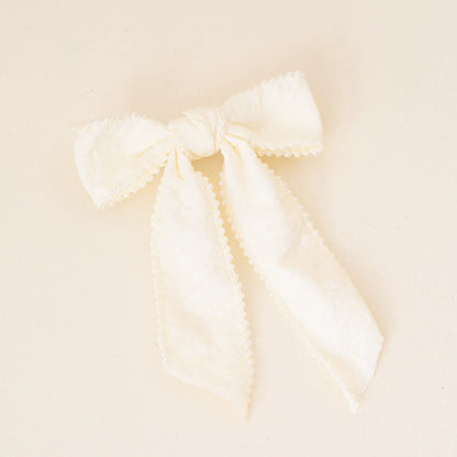 cream bow with pearls shown on an off-white background.