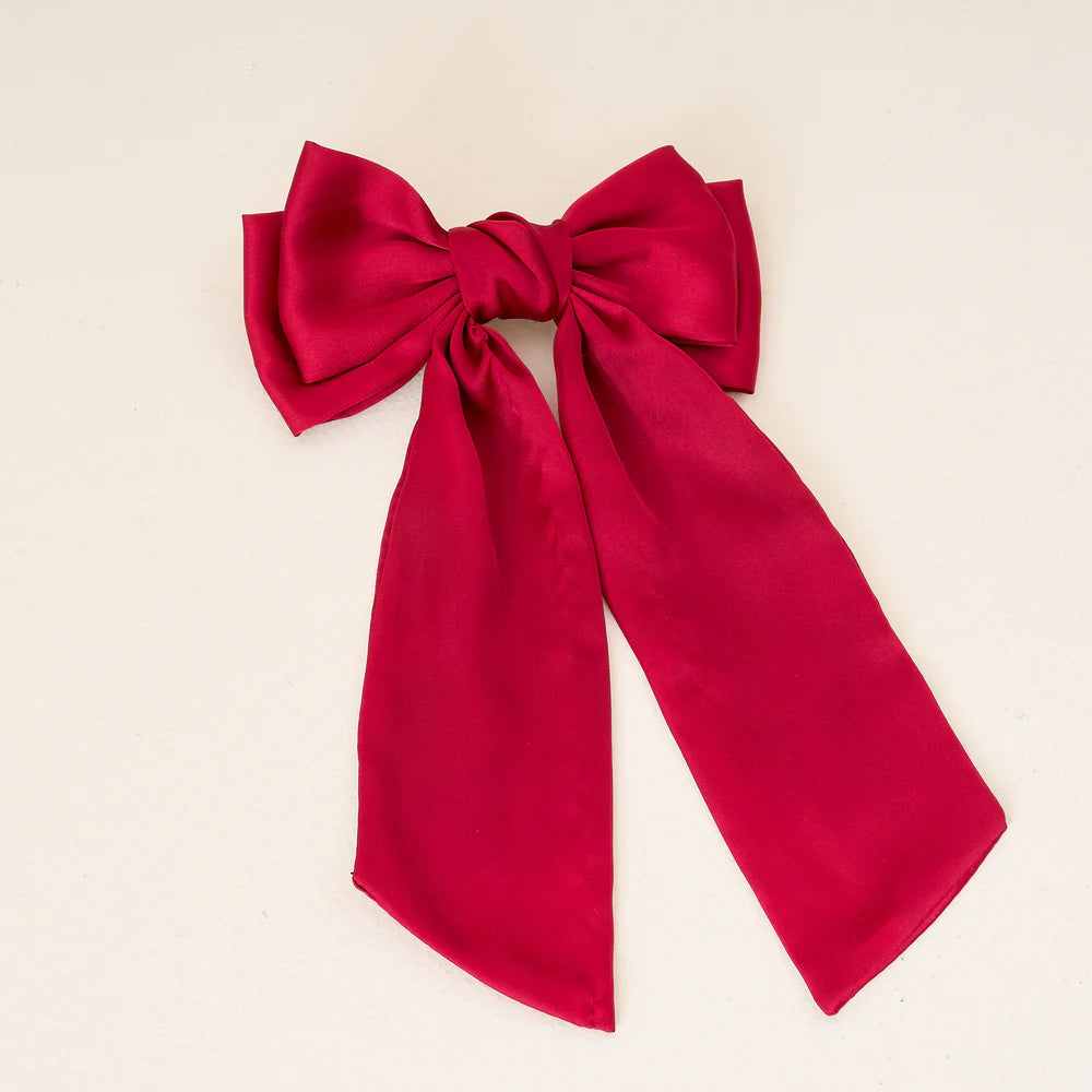 red satin hair bow laying on a white background.