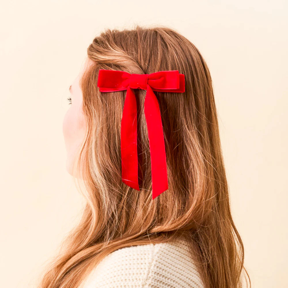 person with light brown hair with red velvet bow clipped in it.