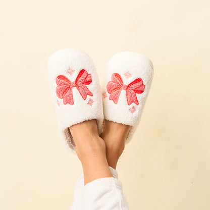 feet crossed in the air wearing white fuzzy slippers with pink bows on the.