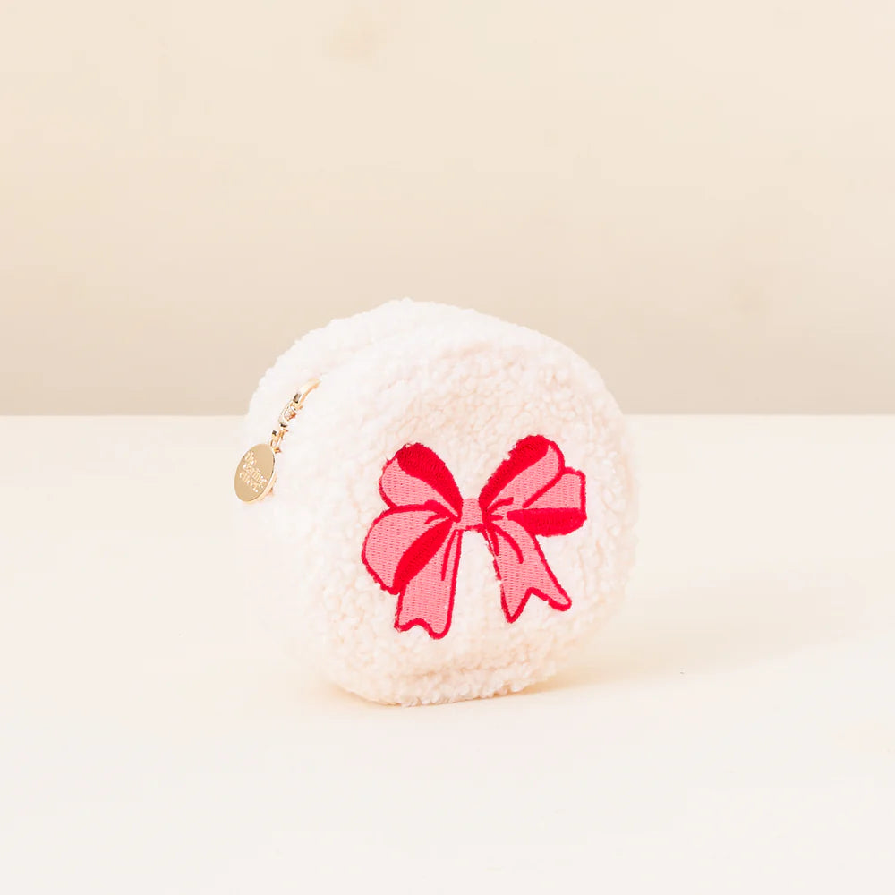 white fuzzy zipper bag with pink and red bow embroidered on it.