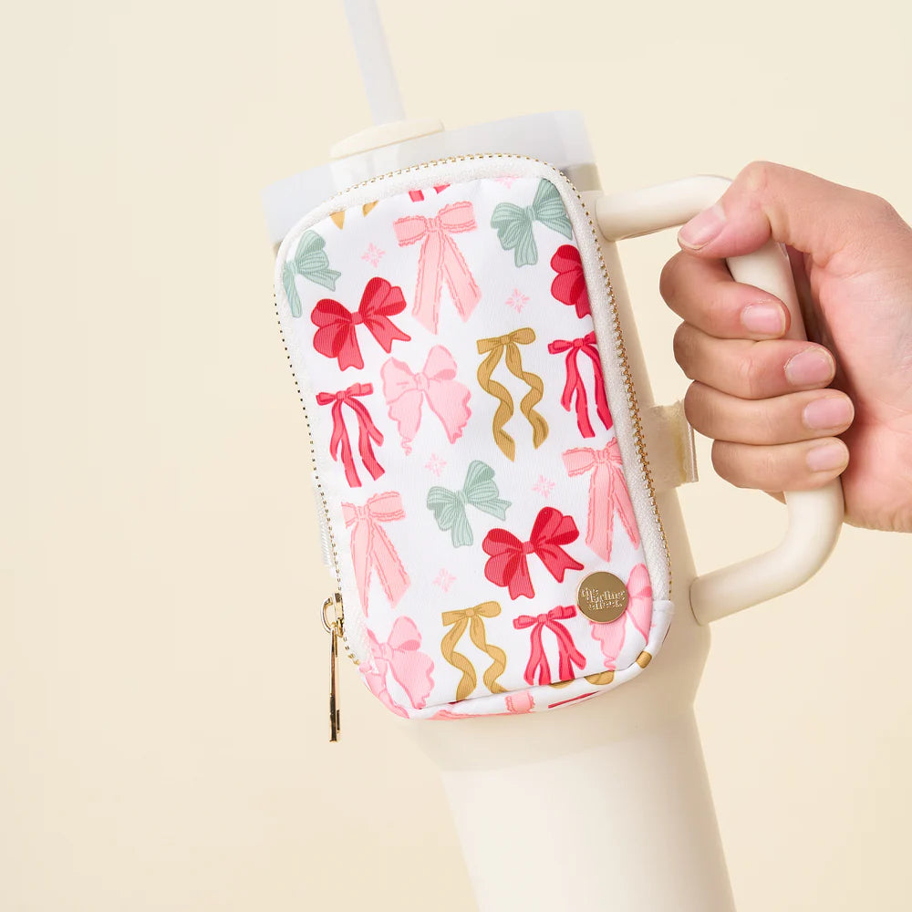 bow affair white zipper pouch printed with an all-over design of colorful bows and strapped with a tumbler.