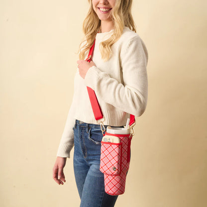 person wearing jeans and a cream colored sweater with a pink and red plaid tumbler sling over their shoulder.