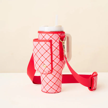 pink and red plaid tumbler sling  with a red strap and phone pocket on it.