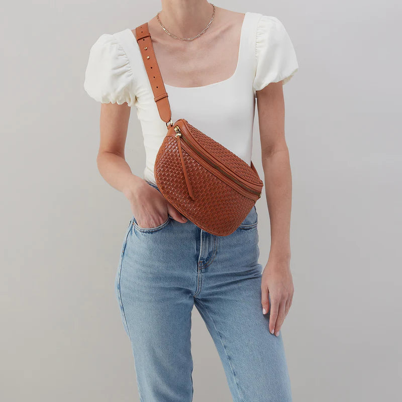 personw wearing jeans and a white top with wheat juno bag across their chest.