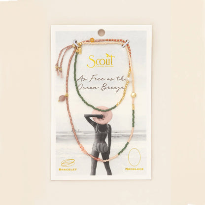beaded wrap in pink, green, and gold hues with accent beads on its card packaging
