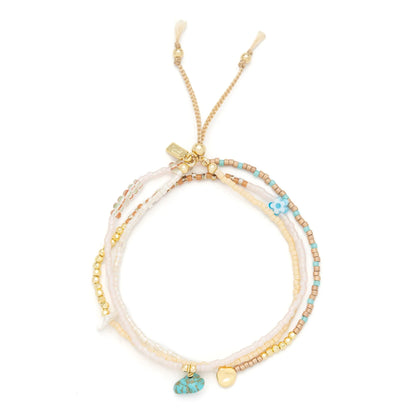 beaded wrap in blush pink and gold hues shown laying as a triple layered bracelet on a white background
