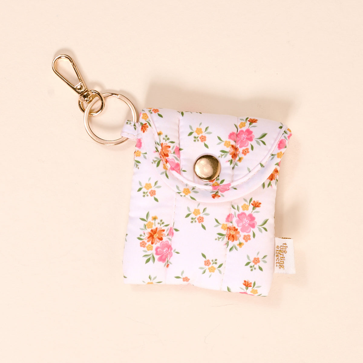 the Puffy Earbud Case Keychain in pattern Endless Daydream Cream on a beige background