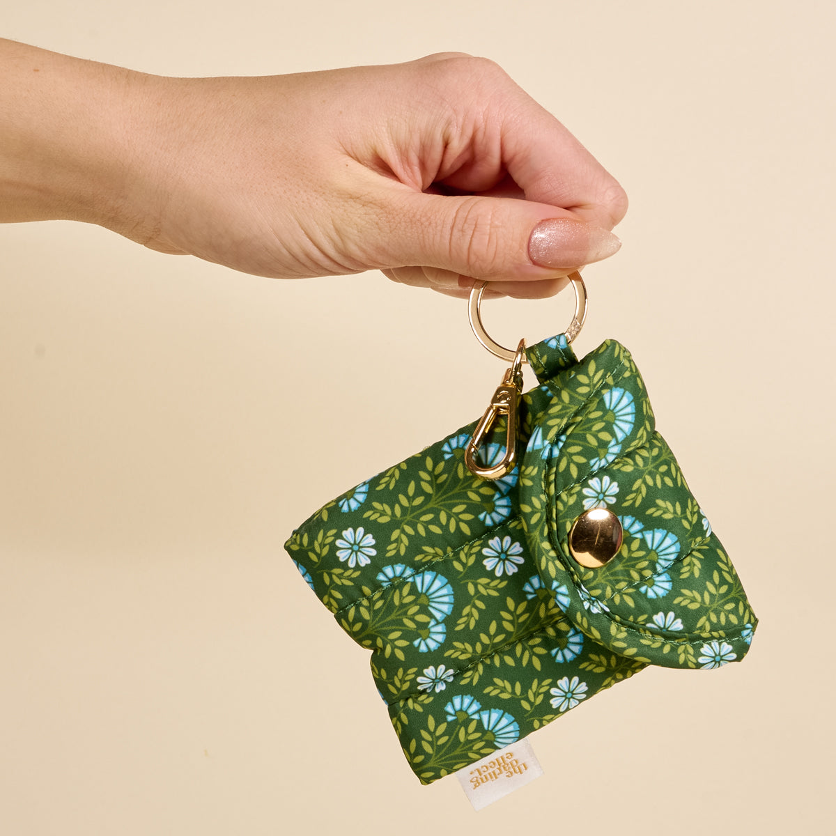 a person holding the Puffy Earbud Case in pattern Everbloom Forest Green