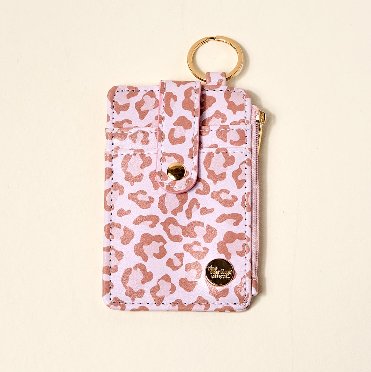pink animal print keychain pouch with gold ring and visible brand logo on a beige background