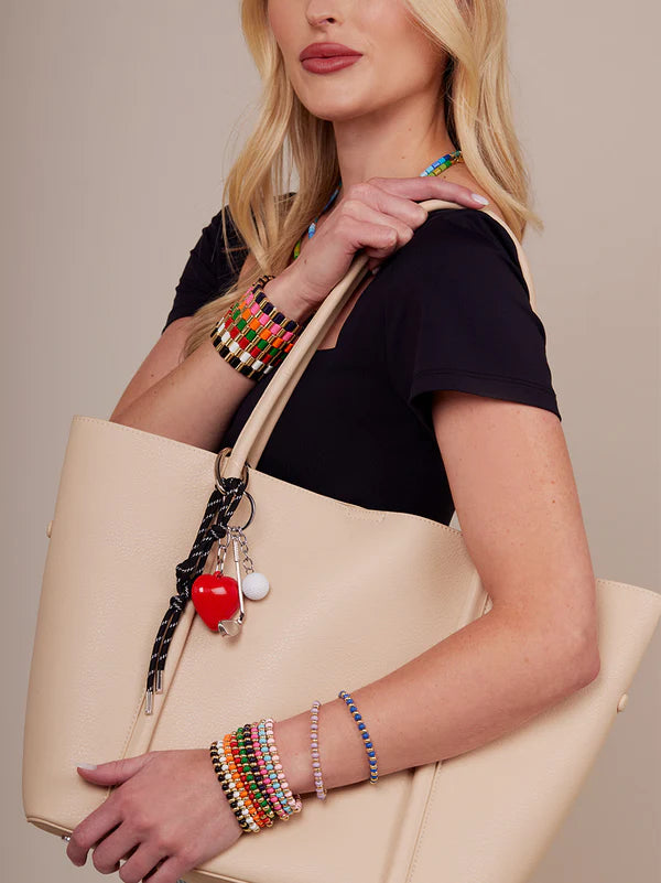 person holding a beige tote with golf bag charm clipped on it