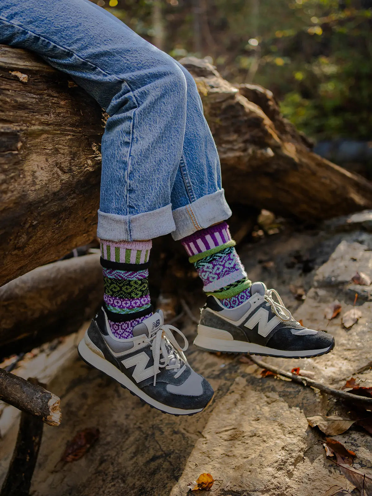 person wearing jeans, tennis shoes and La Seine Crew Socks sitting a fallen log in the forest