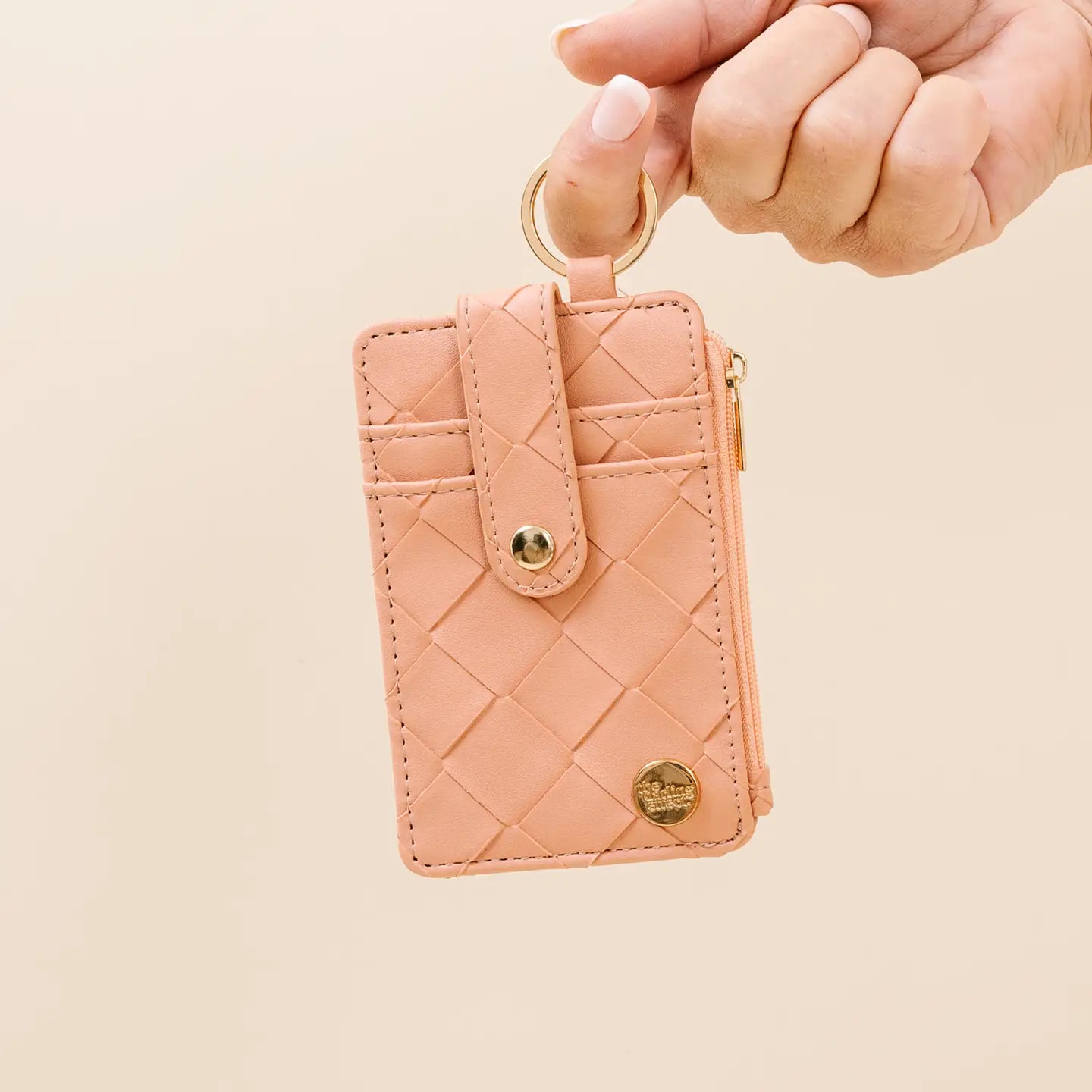 person holding rose Woven Keychain Wallet with their finger by the gold ring key chain on a light beige background