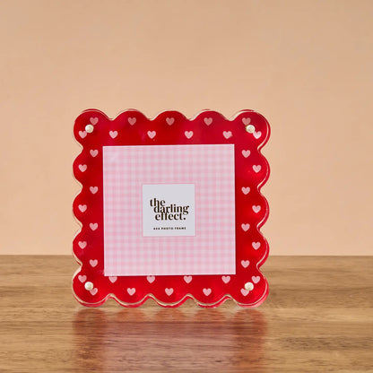 Red frame with pink heart-pattern  on a wooden surface with a beige background