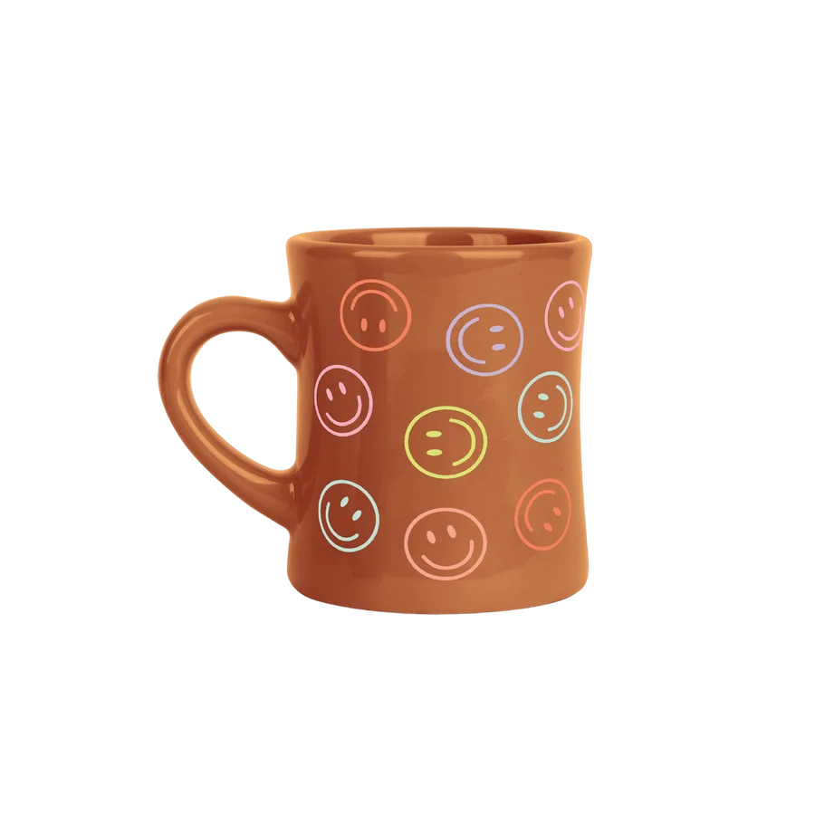 A terracotta brown ceramic mug decorated with a pattern of colorful smiley faces in various outlines, shown against a plain white background.