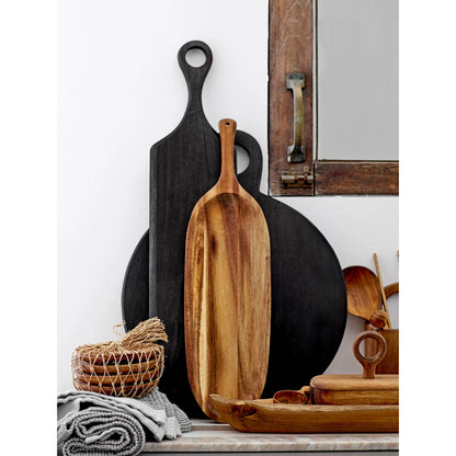 assorted boards leaned against a wall with cabinetry and kitchen utensils on the counter.