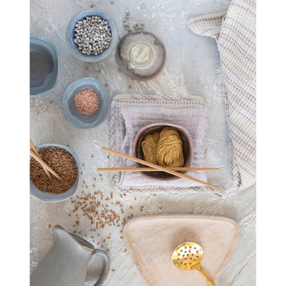 top view of the stripe woven cotton tea towel laying next to bowls of spices, trays, and pitcher on a light gray surface