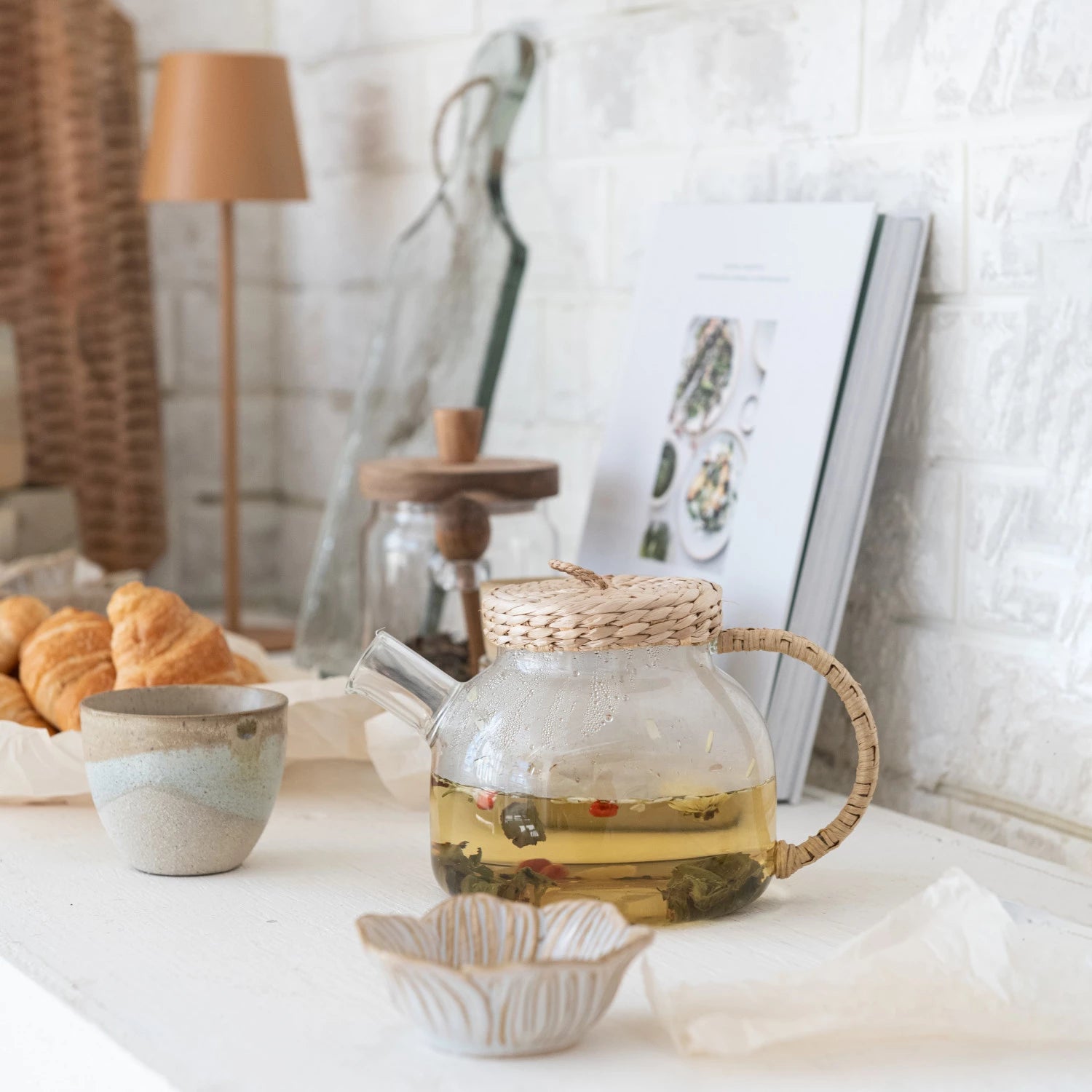 Tea set with a glass teapot and ceramic cups on a table with a kitchen blurred background