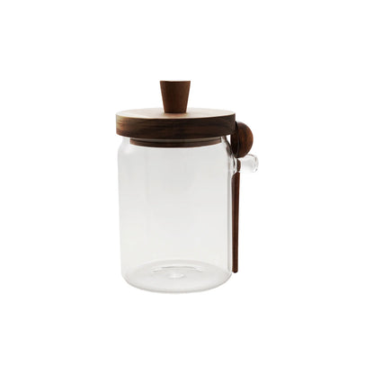 Clear glass jar with wooden lid and spoon hangs on the side of it