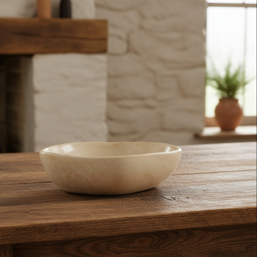 stoneware serving bowl set on a wooden surface in a home setting with a window in the background