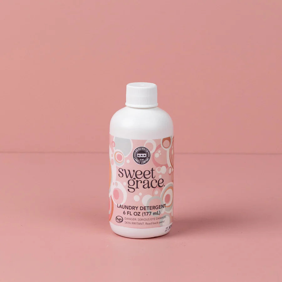 bottle of sweet grace laundry detergent shown on a pink background
