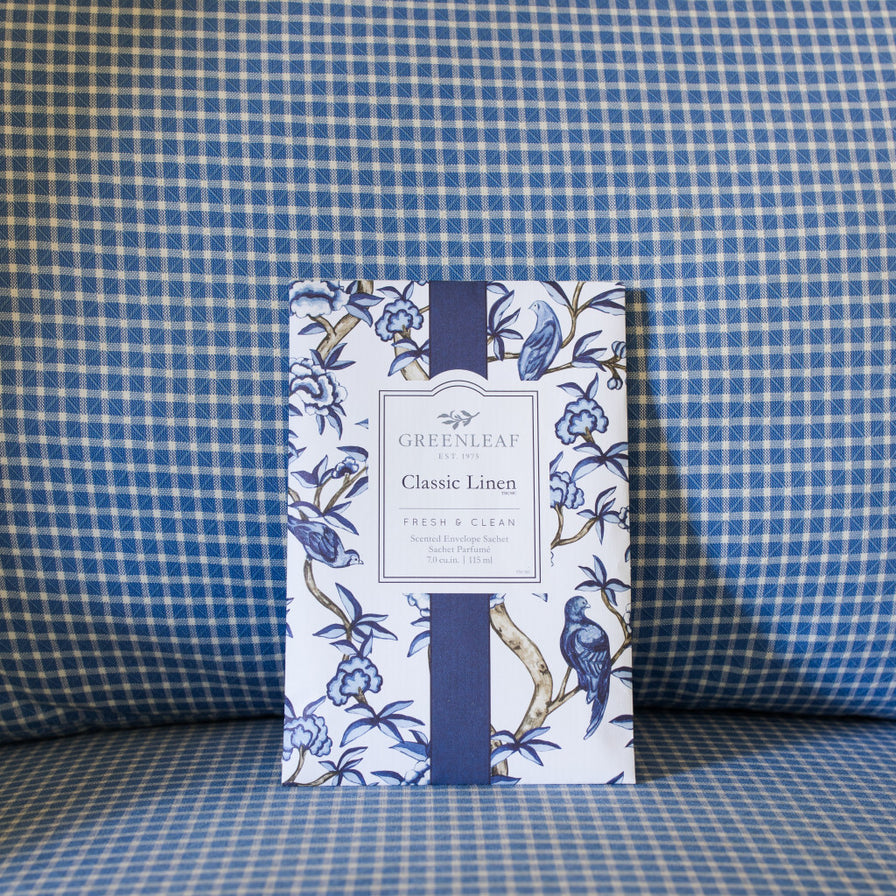 Classic Linen Large Sachet printed with a blue and white design set on a blue plaid cushion.