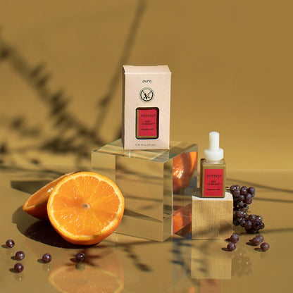 Red Currant Pura Fragrance Refill on a block of wood with its box packaging arranged with berries and sliced oranges.