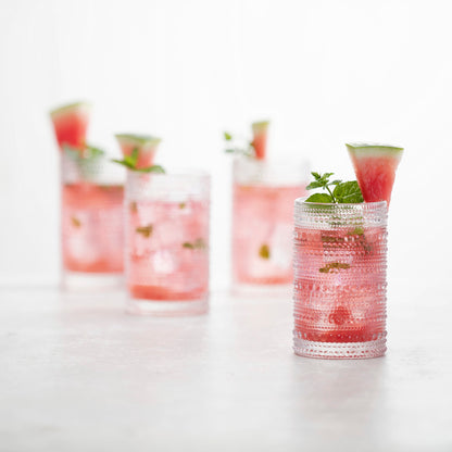 4 clear jupiter iced beverage glasses filled with pink beverage and garnished with fruit. 
