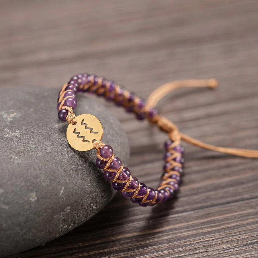 Aquarius bracelet draped on a stone on a wooden table.