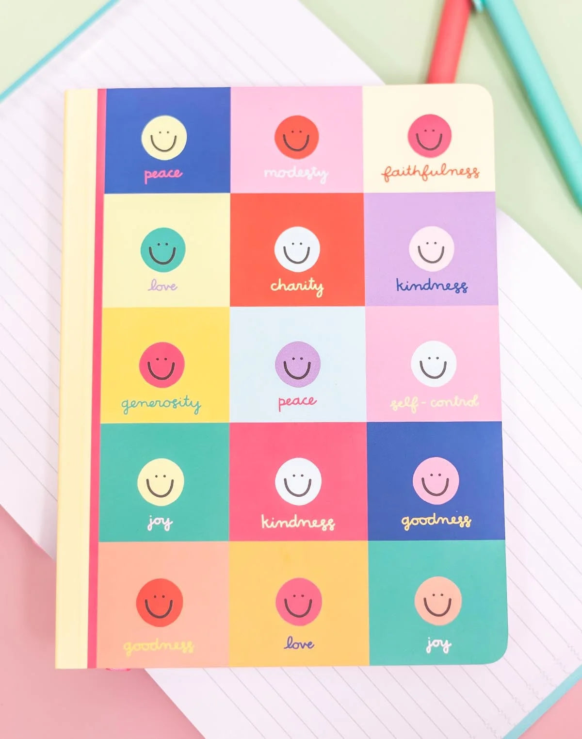 Notebook with smiley face design and positive words on a colorful background