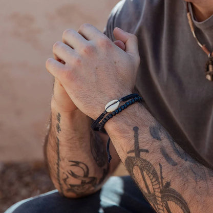 Person with tattoos wearing a bracelet on a blurred natural background