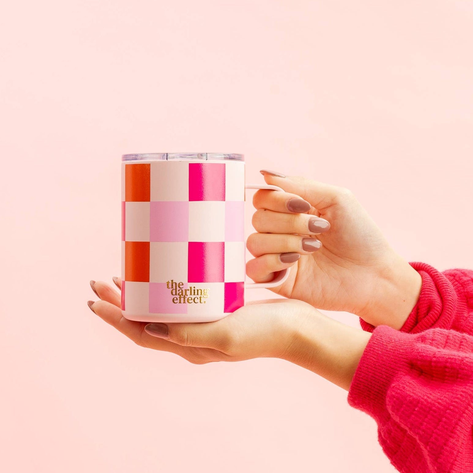 hands holding sweetheart check insolated mug on a pink background.