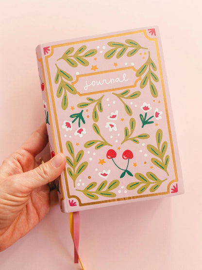 person holding a notebook against a pink background