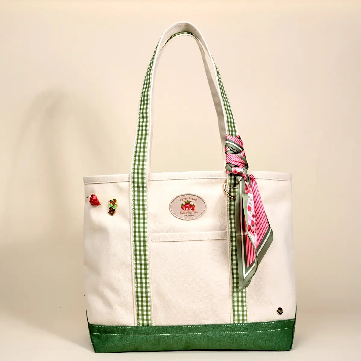 Off-White tote bag with green accents and a pink scarf, on a beige background