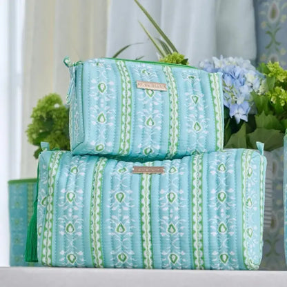 small and large Signature Cosmetic Bag with the Rosemary Stripe pattern stacked on top of each other with flowers in the background