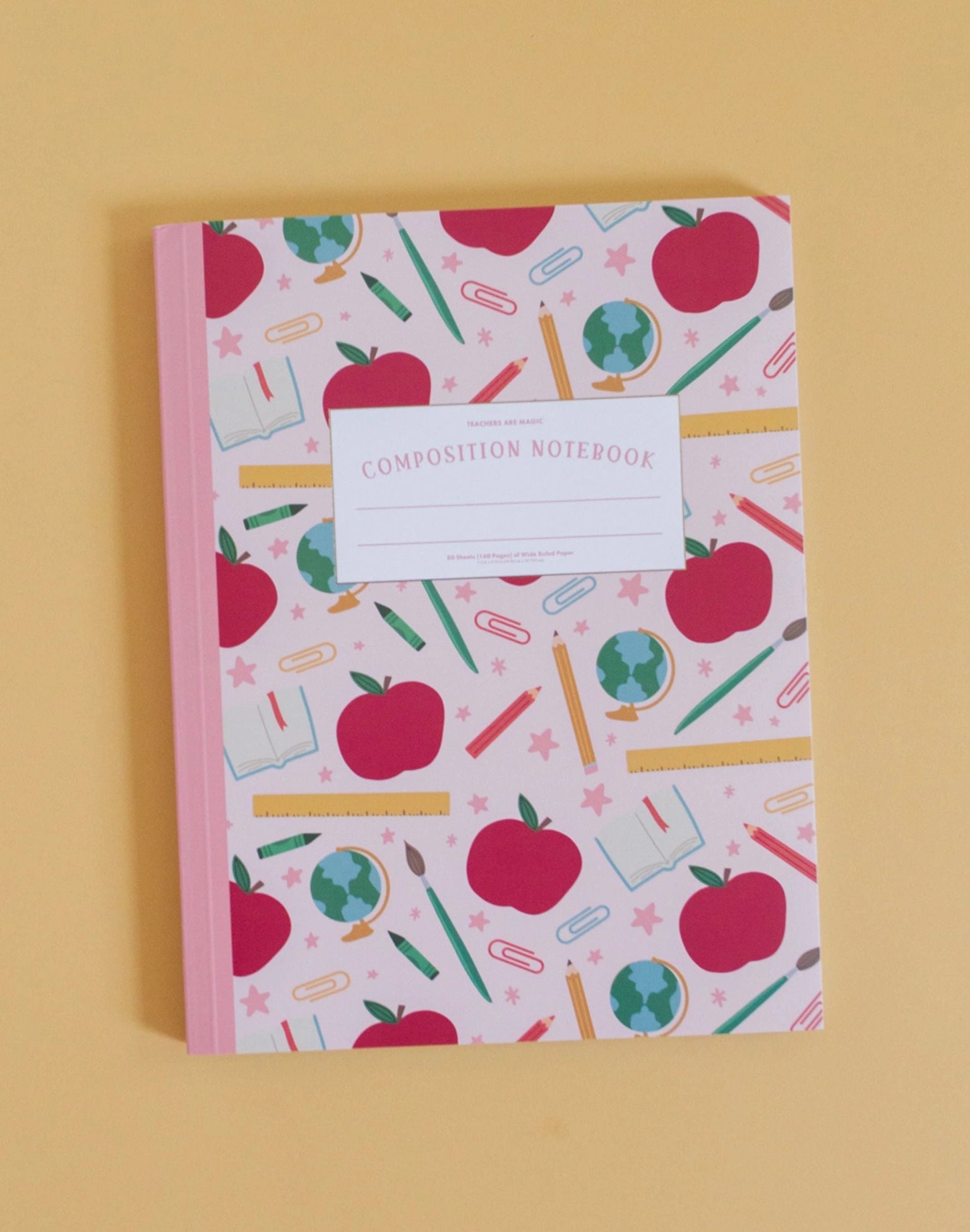 pink notebook with school themes images on it shown on a beige background