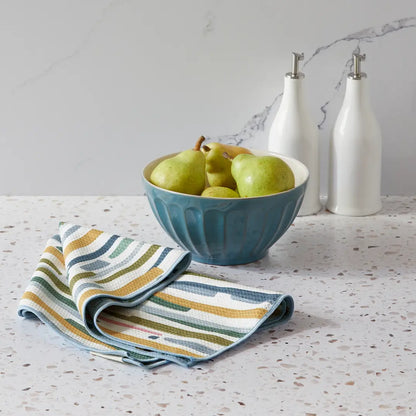 Abstract side of towel draped on a countertop next to a bowl of pears.