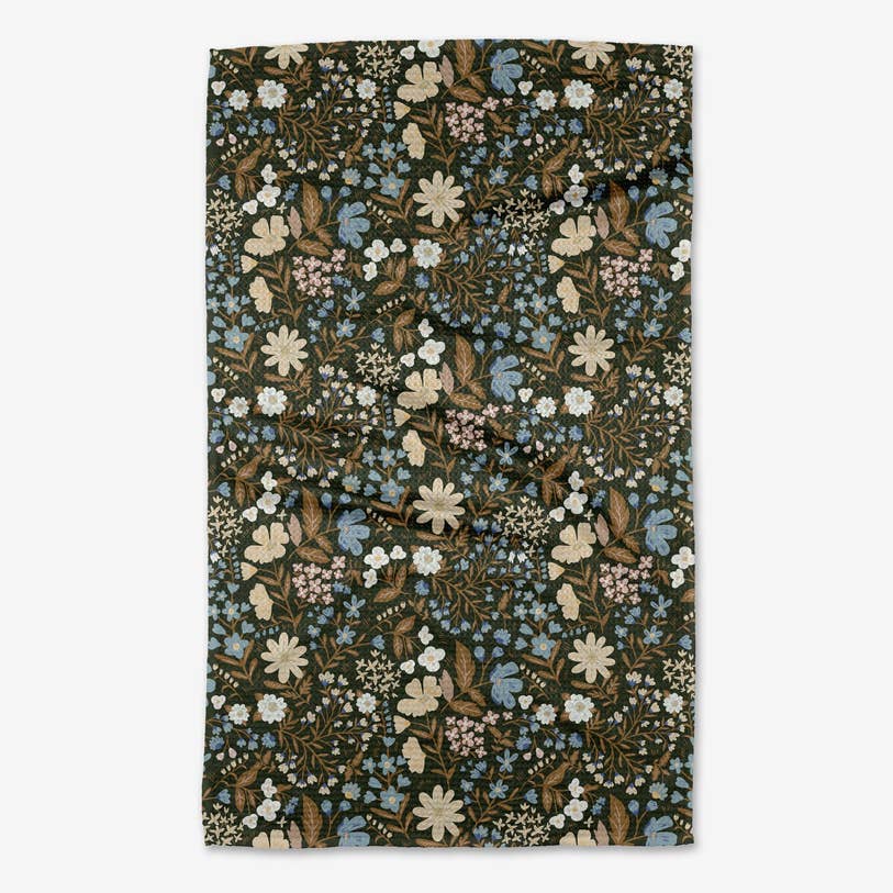 cottage meadow sepia tea towel with an all-over pattern of wild flowers in muted hues of beige, brown, and blue on a deep green background