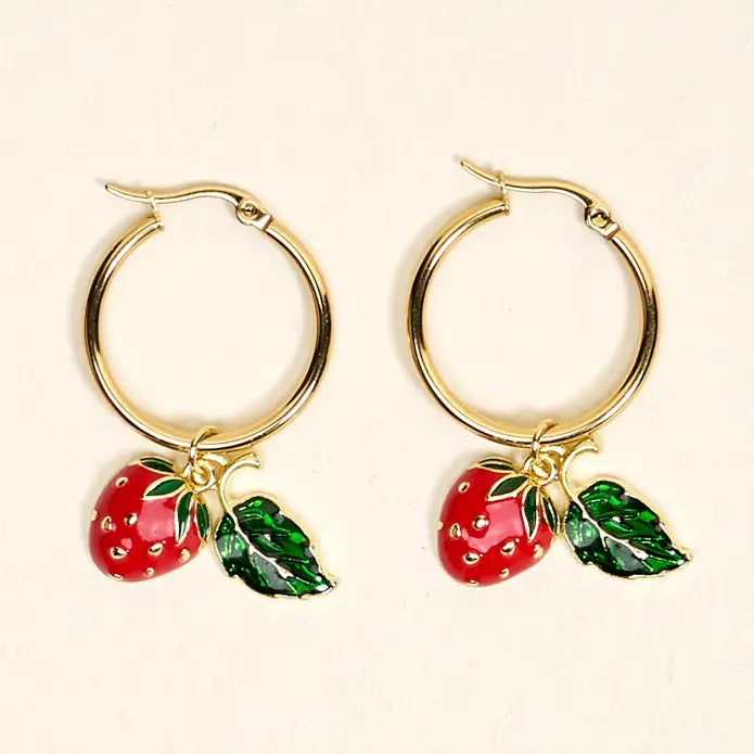 Gold hoop earrings with red strawberry charms on a beige background