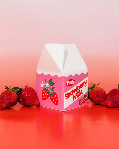 strawberry milk vase on a red surface with strawberries.