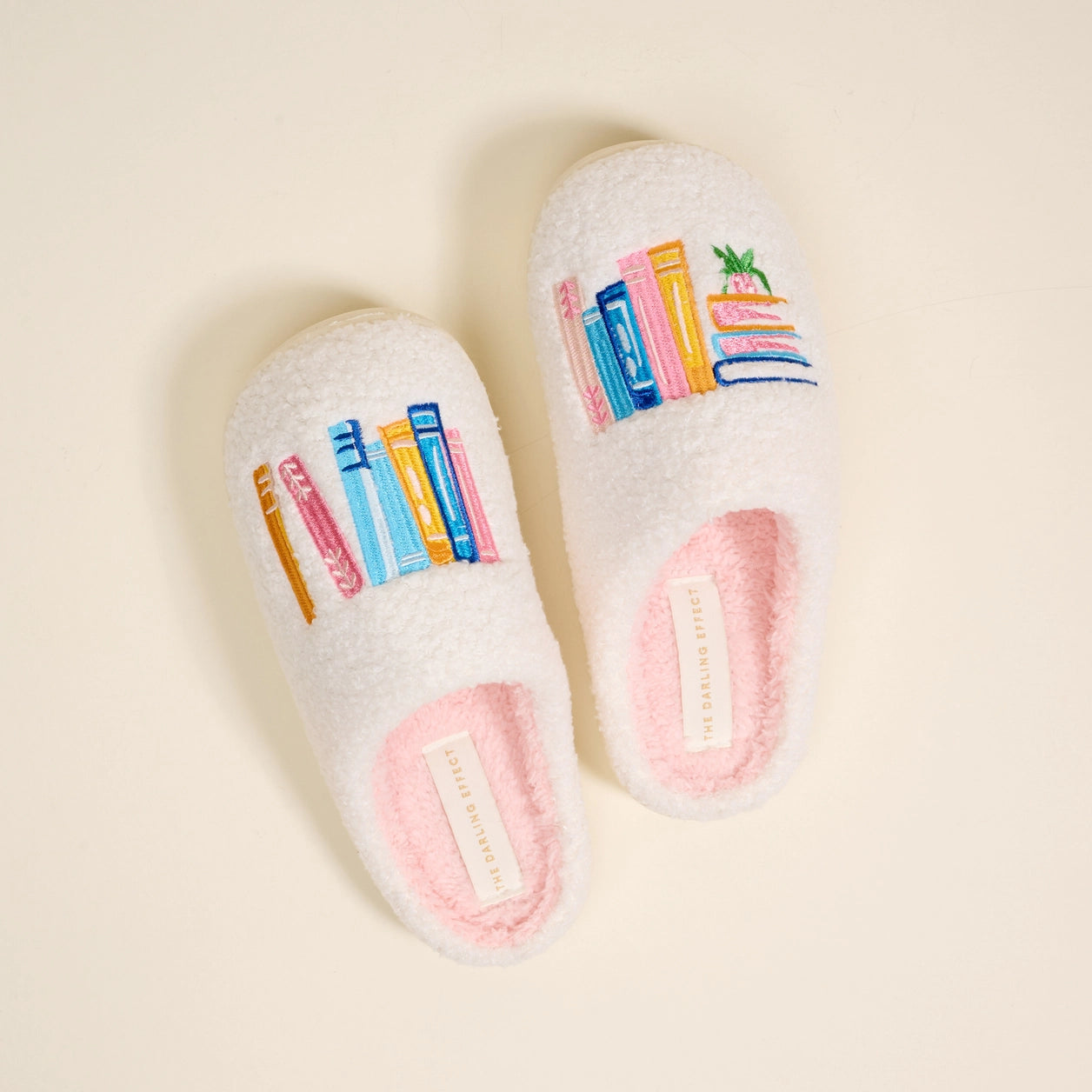 Pair of white slippers with colorful book design on a beige background
